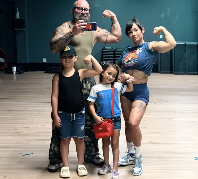 Shannon Cain flexing in the gym with his wife and two of their kids
